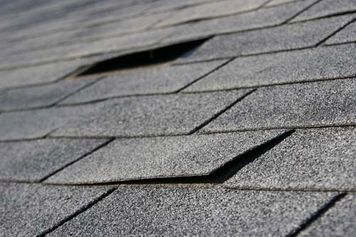 Closeup of peeling shingles from storm damage.