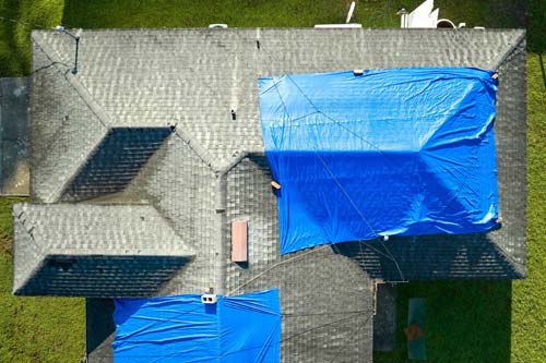 Blue tarp over damaged roofing.